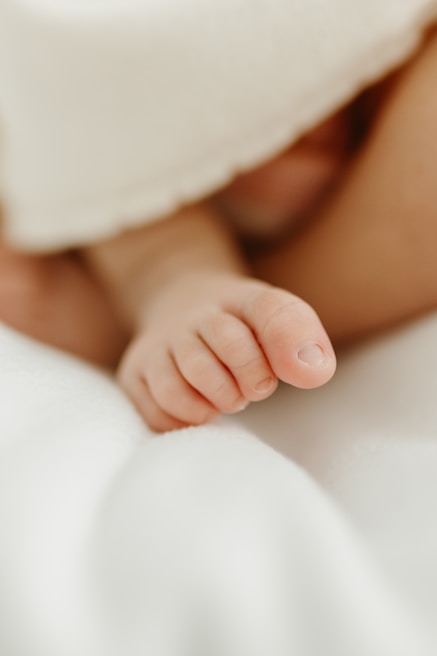 Close-up of a tiny baby sock resting gently on a wooden table, representing the journey ahead.