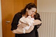 A mother holding her newborn baby in a cozy maternity ward filled with natural light.