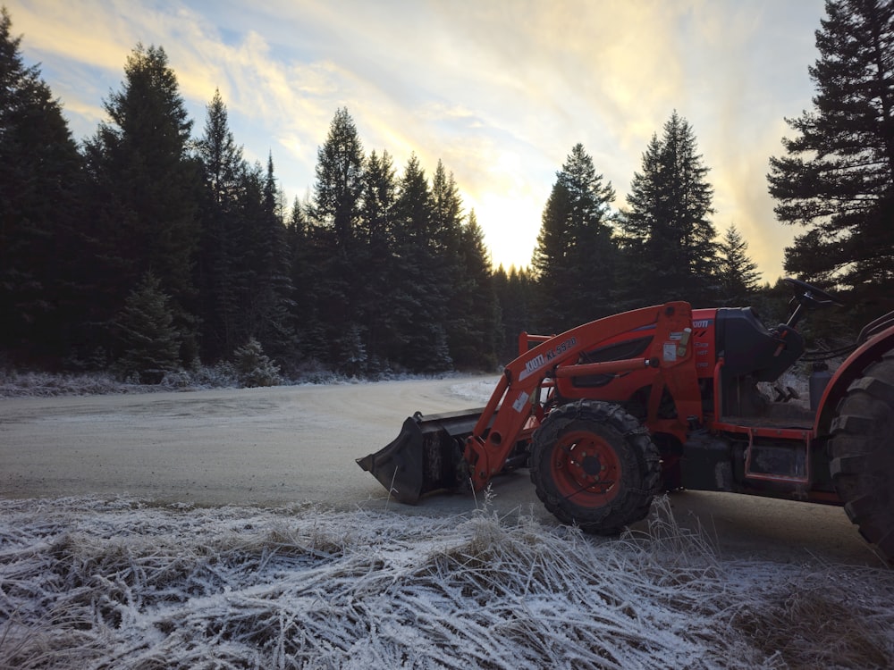 a red tractor is driving through a frozen field