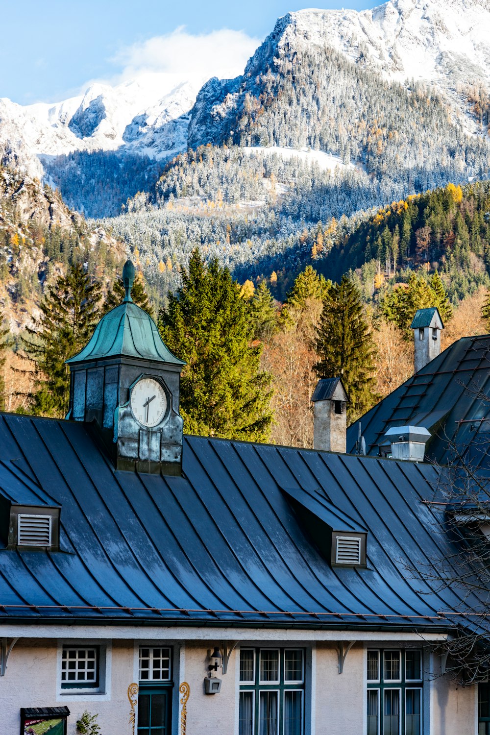 a clock on the roof of a building with mountains in the background