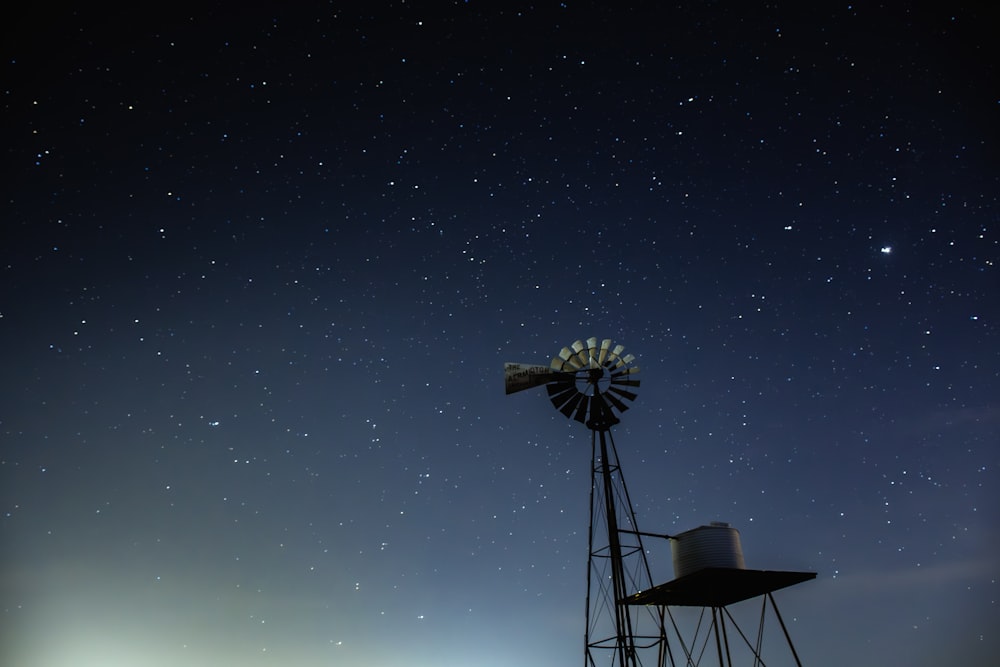 un moulin à vent avec un ciel plein d’étoiles en arrière-plan