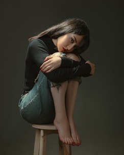 a woman sitting on top of a wooden stool