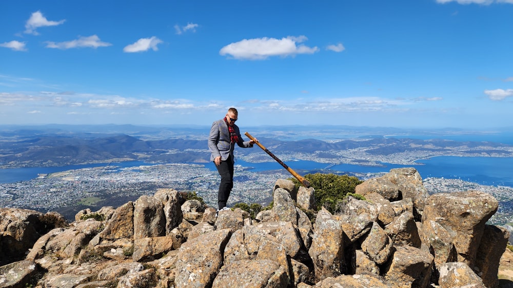 a man standing on top of a mountain holding a stick