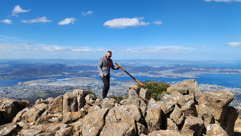 un hombre parado en la cima de una montaña sosteniendo un palo