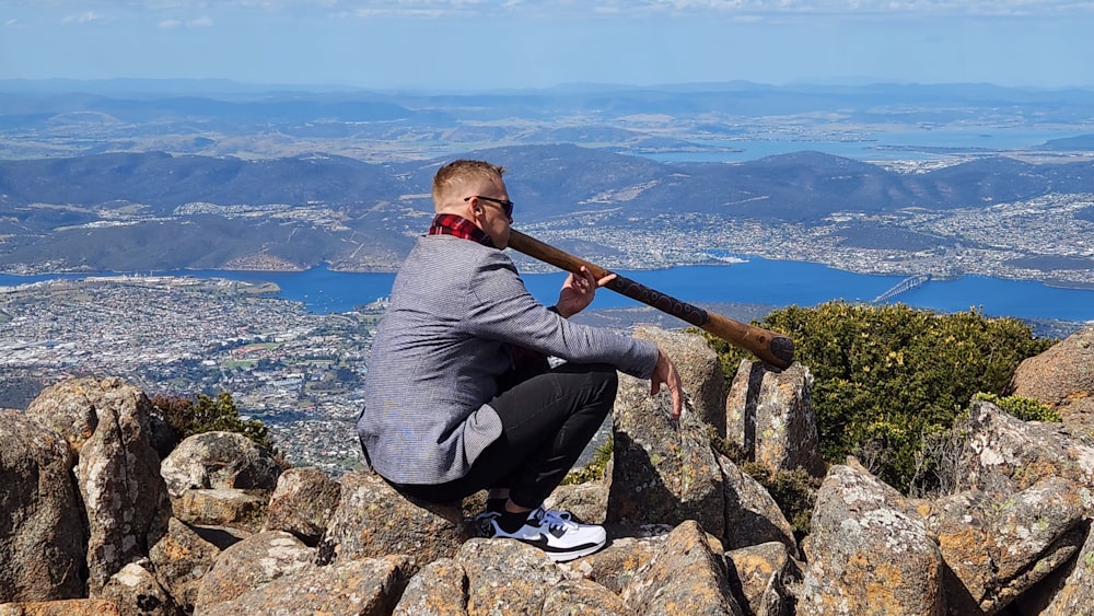 a man sitting on top of a mountain holding a baseball bat