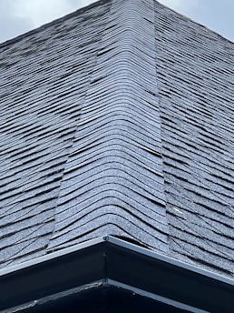 A close-up of a freshly installed shingle roof glistening under the morning sun.