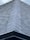 A close-up view of a roof with dark, overlapping shingles creating a textured surface. The shingles appear to be evenly laid with a symmetrical design.