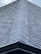 A close-up view of a roof with dark, overlapping shingles creating a textured surface. The shingles appear to be evenly laid with a symmetrical design.