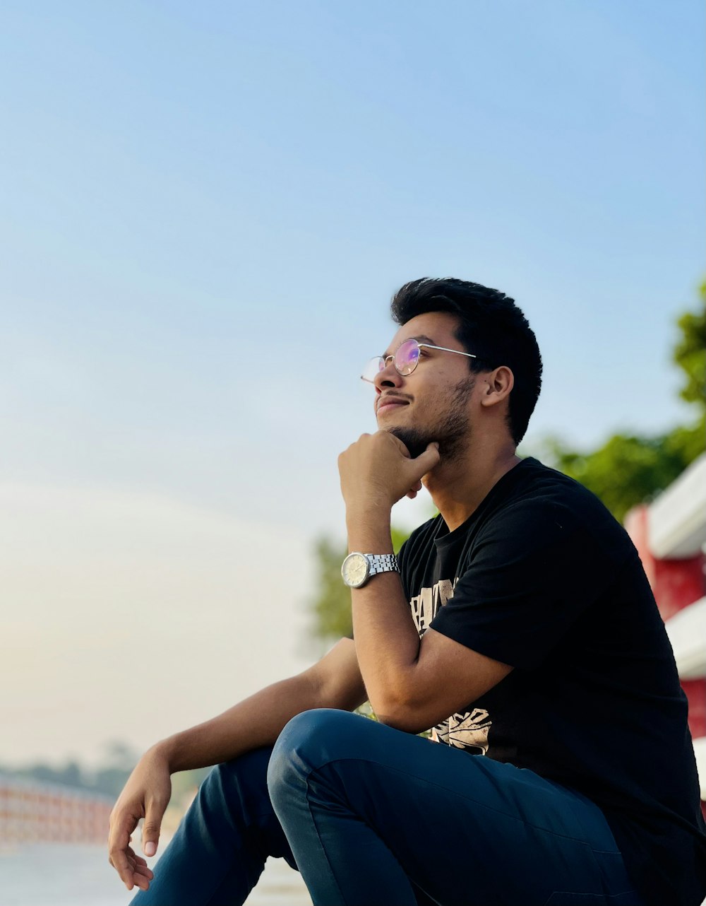 a man sitting on a ledge with his hand on his chin