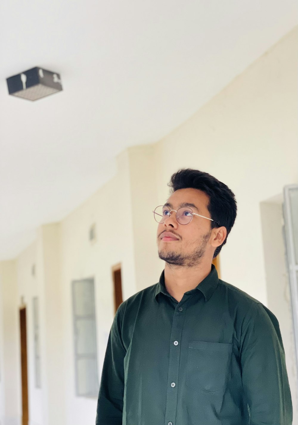 a man in a green shirt standing in a hallway