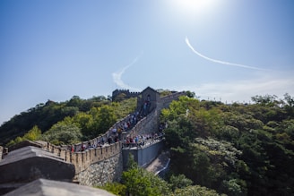 A traveler happily booking tickets on a sleek laptop with a backdrop of the Great Wall of China.