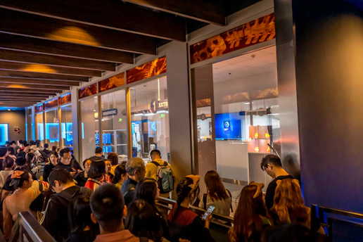 A busy DMV office with people waiting in line and a digital wait time display