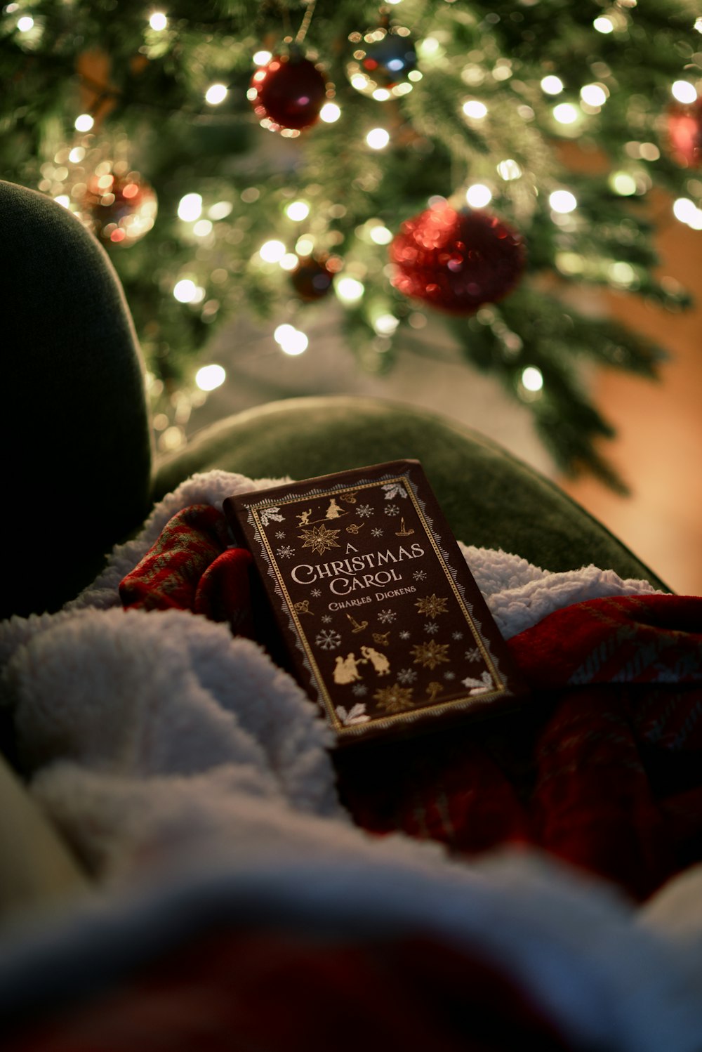 a book sitting on a blanket in front of a christmas tree