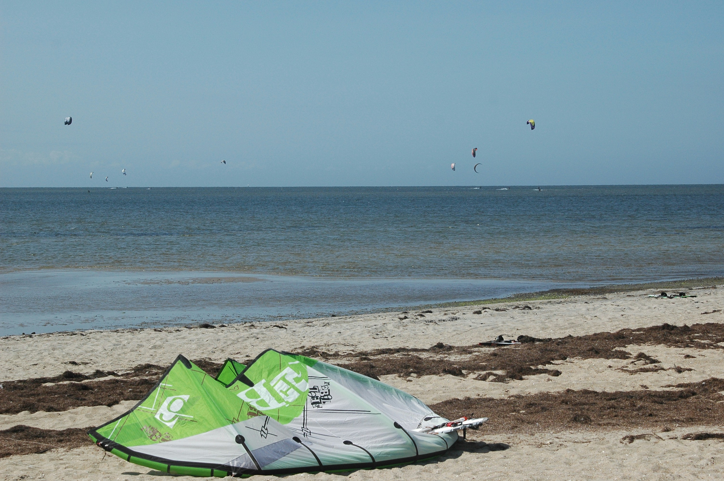 a green and white kite sitting on top of a sandy beach, 