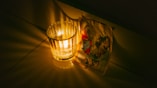 a glass of water sitting next to a lit candle
