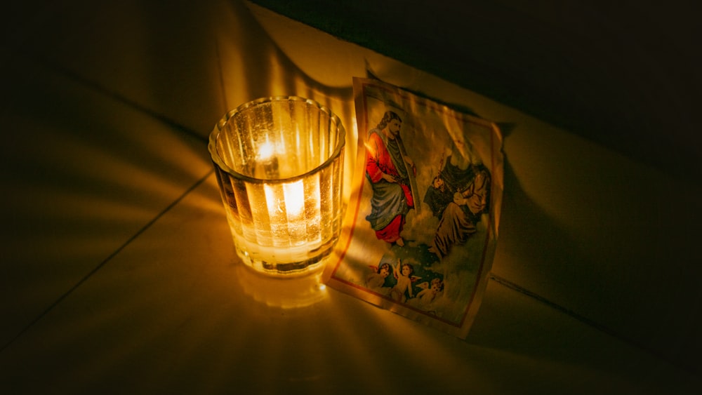 a glass of water sitting next to a lit candle