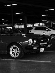 a black and white photo of two cars in a parking garage