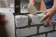 Close-up of hands mixing cement for a wall.