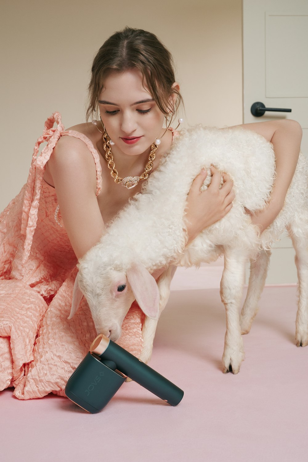 a woman in a pink dress is petting a sheep