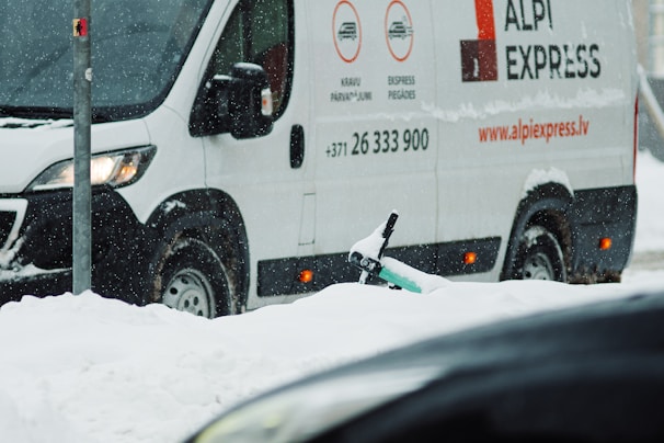 A Canadian delivery truck with Afkas Auto Parts branding driving through a snowy Sudbury street.