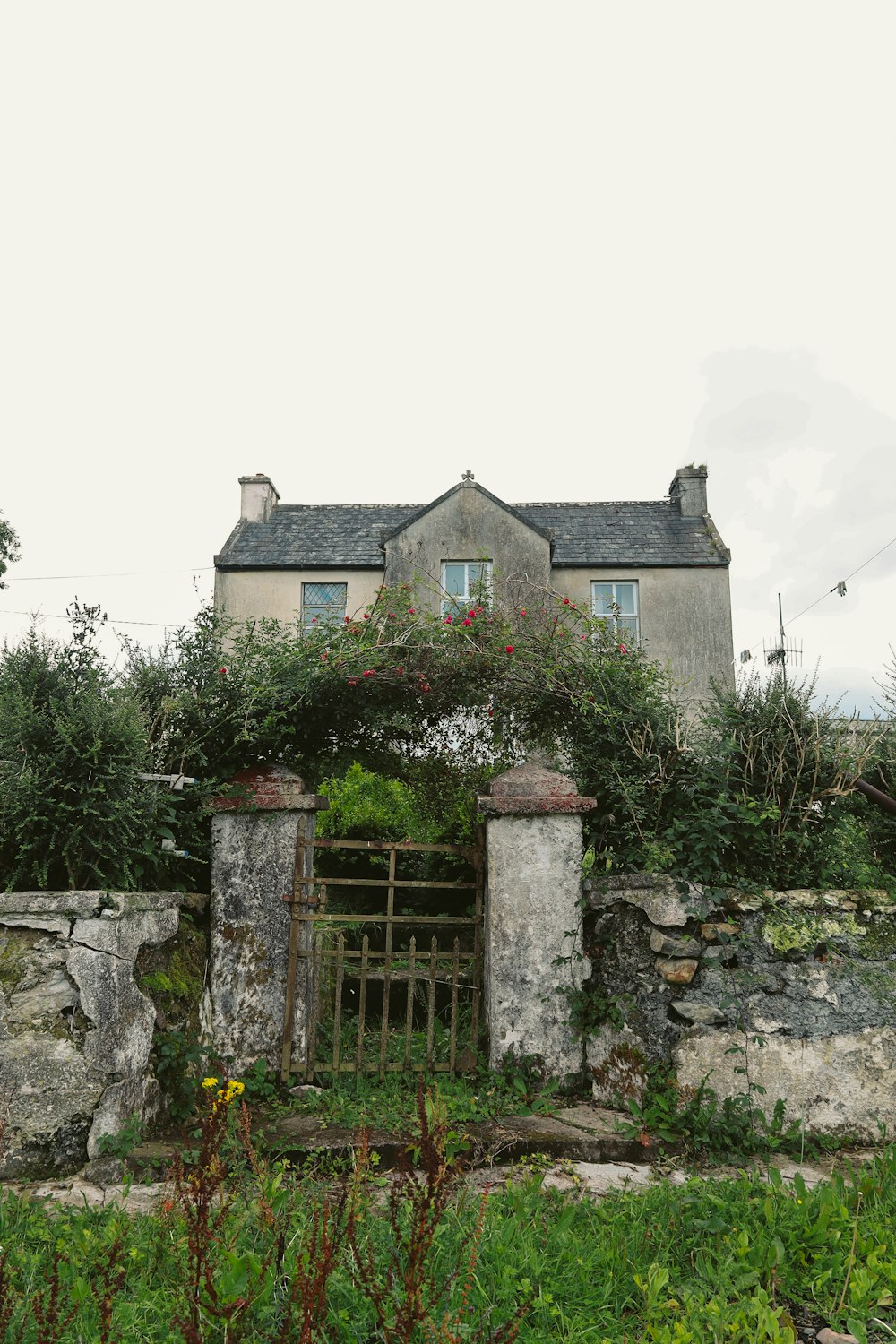 an old stone house with a gate in front of it
