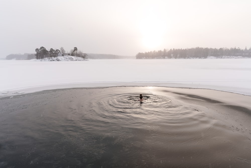 a person in a body of water surrounded by snow