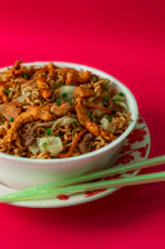 A steaming bowl of stir-fry noodles with colorful vegetables and tender chicken.