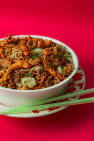 A steaming bowl of stir-fry noodles with colorful vegetables and tender chicken.