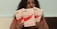 A person with long dark curly hair is holding three boxes labeled QNIX. The packages are of menstrual underwear with labels such as 'Bacoup Period Underwear' and 'High Cut Period Underwear'. The background is plain, and the person has their gaze directed away from the camera.