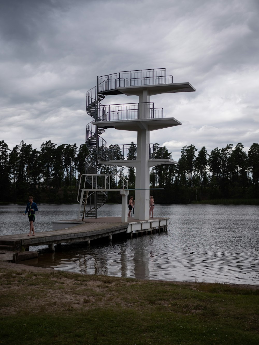 a couple of people standing on a dock next to a body of water