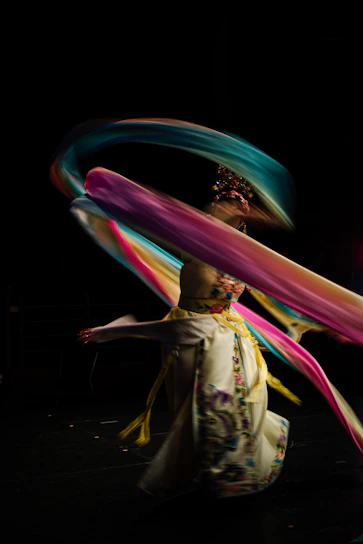 A graceful dancer in a flowing fusion costume mid-twirl, highlighting vibrant colors and intricate details.
