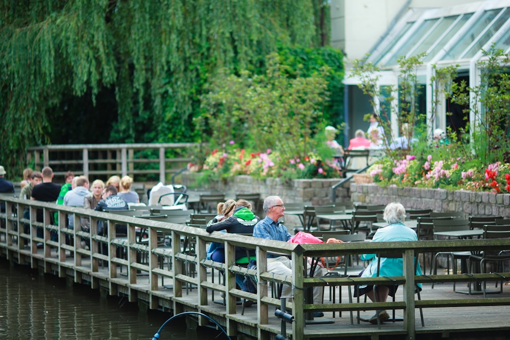 a group of people sitting at tables next to a body of water