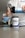 A person pours blue liquid from a shaker bottle into a glass. Next to the glass is a container labeled 'PRE-X' which appears to be a pre-workout supplement. The scene suggests a focus on fitness or nutrition.