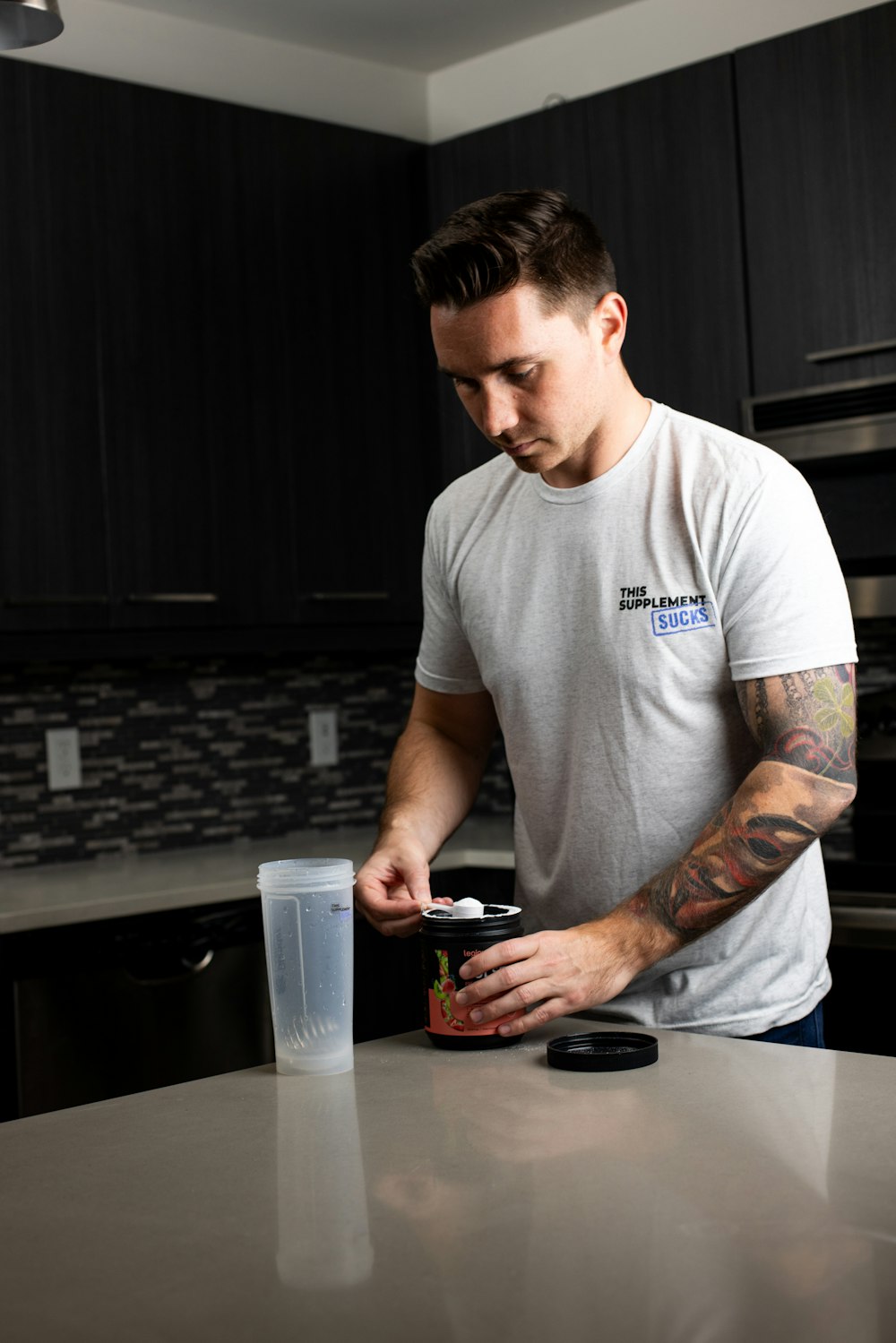 a man standing at a kitchen counter with a drink in his hand