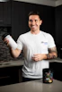 Smiling fitness enthusiast enjoying a post-workout shake with vitaforge branding visible