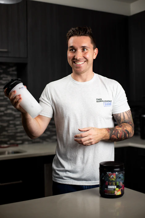 Close-up of a confident man holding a supplement bottle in a bright, modern kitchen