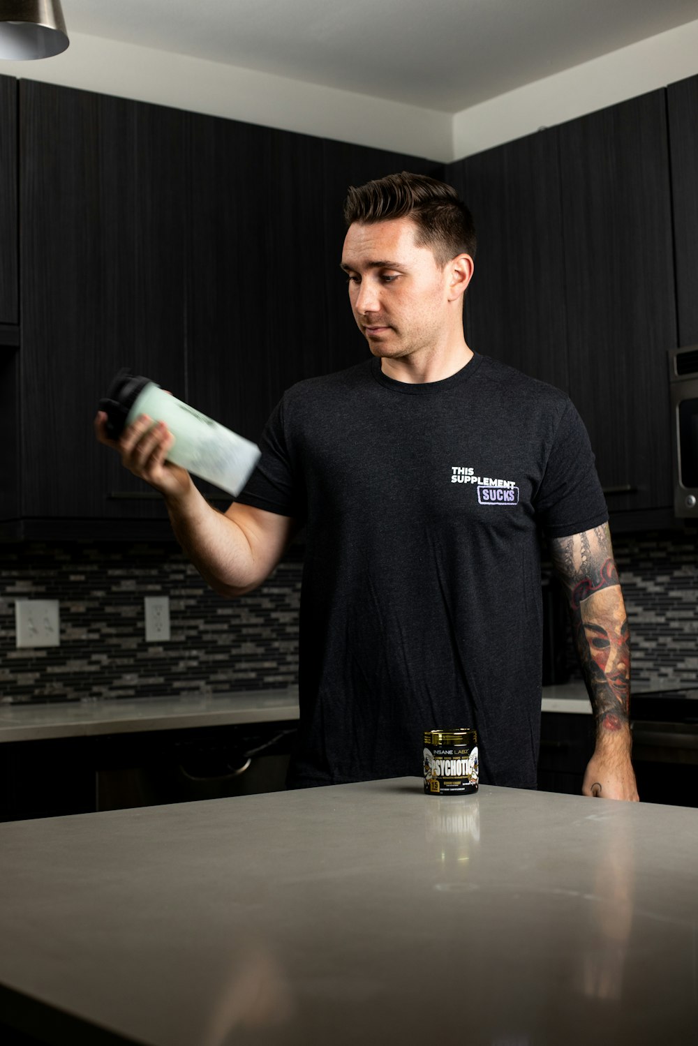a man standing in a kitchen holding a can of soda