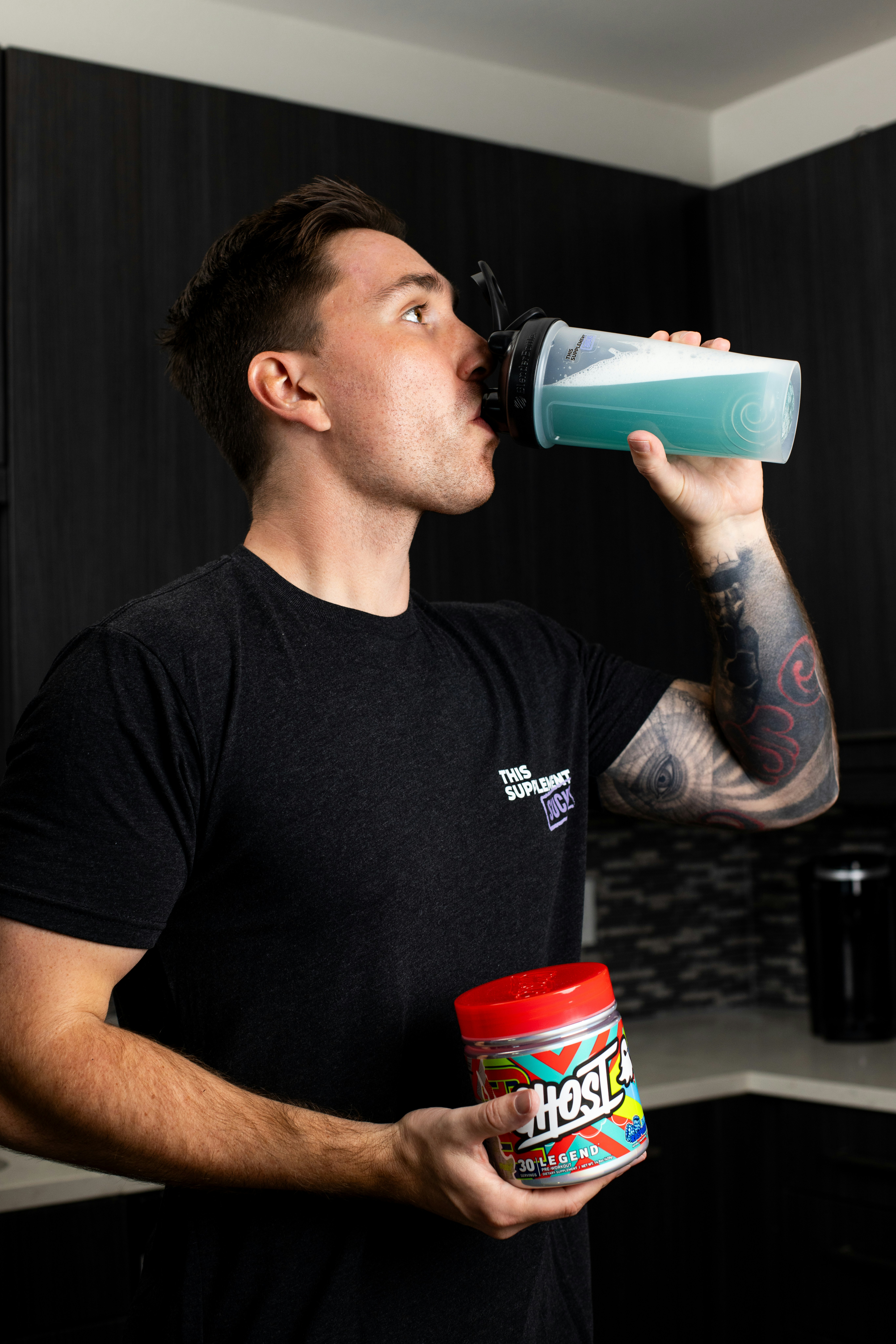 a man in a black shirt drinking from a cup