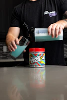 Brightly colored weight gainer shake being poured into a glass.