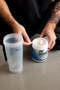 a man holding a spoon over a plastic cup