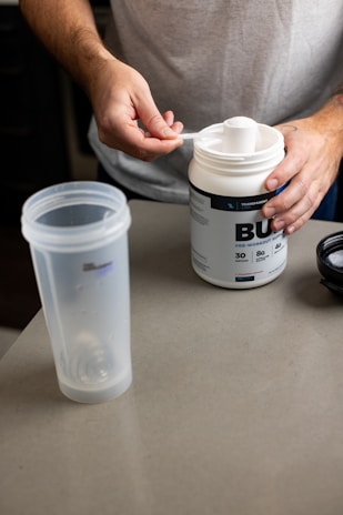 Close-up of a protein supplement powder being scooped into a shaker bottle.