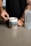 A person is scooping powder from a container labeled 'Oxyshred' with the flavor 'Juicy Watermelon' indicated. The person is wearing a dark shirt and has tattoos on their arm. A translucent shaker bottle is visible on the countertop next to the container.