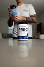 a man holding a bottle of pre - x on a counter