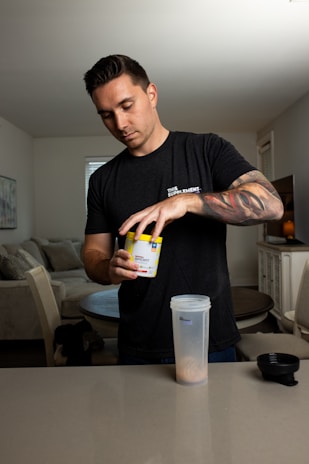 A person preparing a protein shake in a bright kitchen setting.