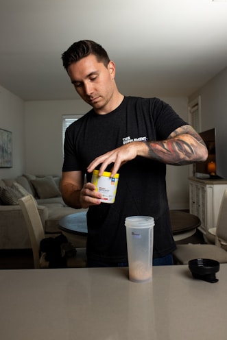 A person preparing a protein shake in a bright kitchen setting.