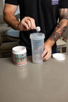 a man standing at a table with a cup and a container
