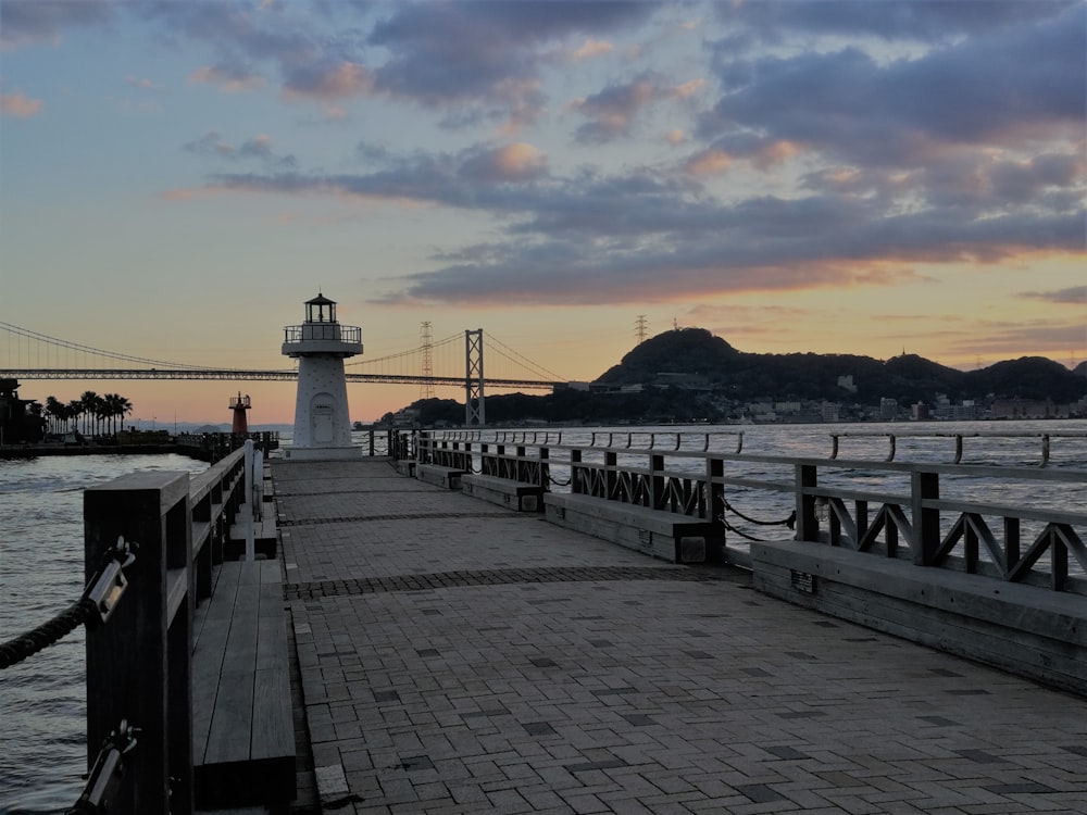 une jetée avec un phare en arrière-plan