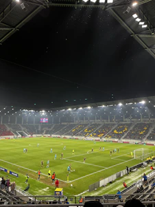 A vibrant scoreboard displaying live soccer match results under stadium lights.