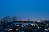 A bustling cityscape viewed from a high rooftop during twilight.