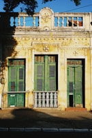a yellow building with green shutters and a balcony
